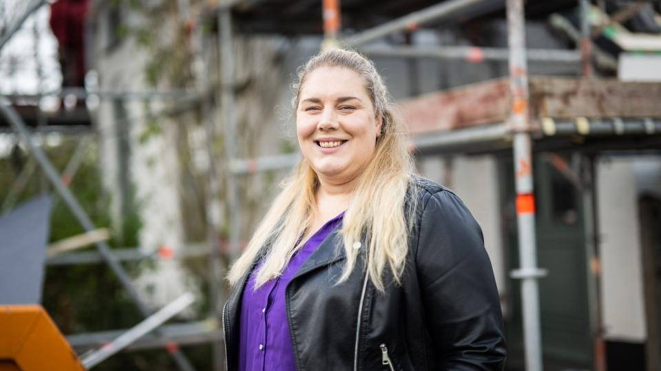 Blije vrouw bij haar verbouwde huis