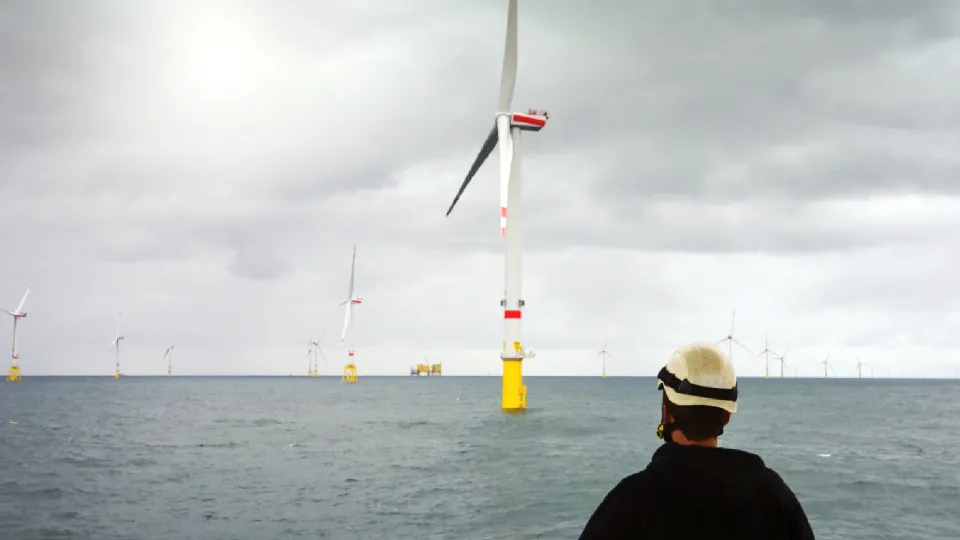 Beeld op zee van windmolen + man