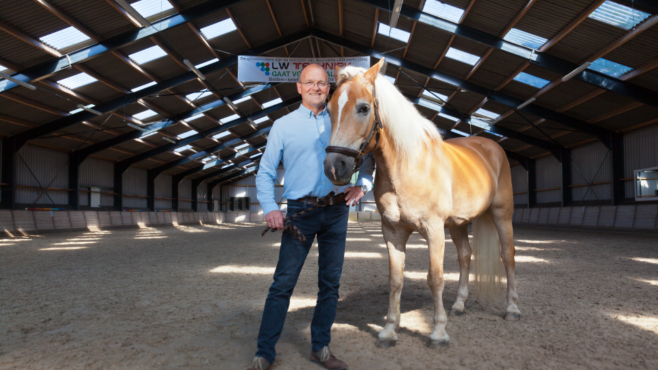 Foto Bert Vos, voorzitter van de Stroomruiters, naast een paard.