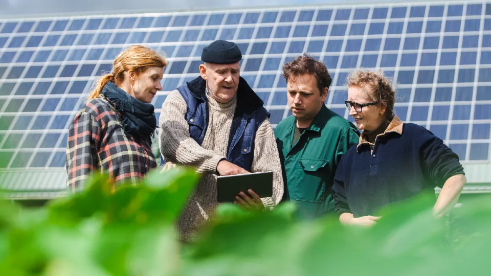 Kennisaanbieder en boeren op het land kijken naar Ipad. Kennisaanbieder laat resultaten zien. 