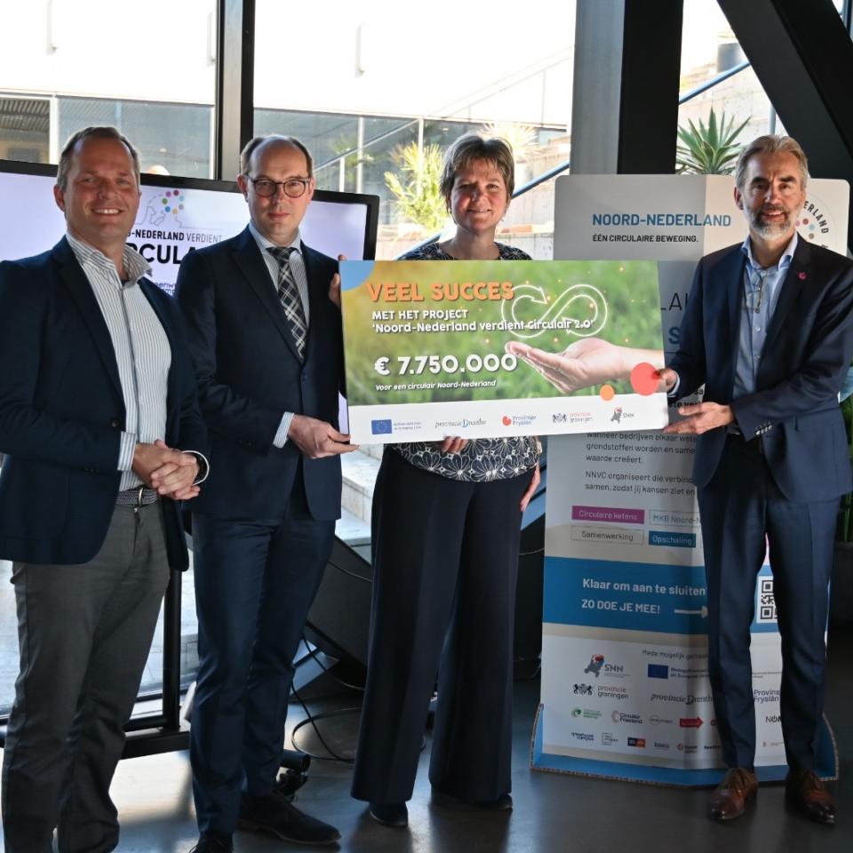 3 mannen en 1 vrouw met een cheque 