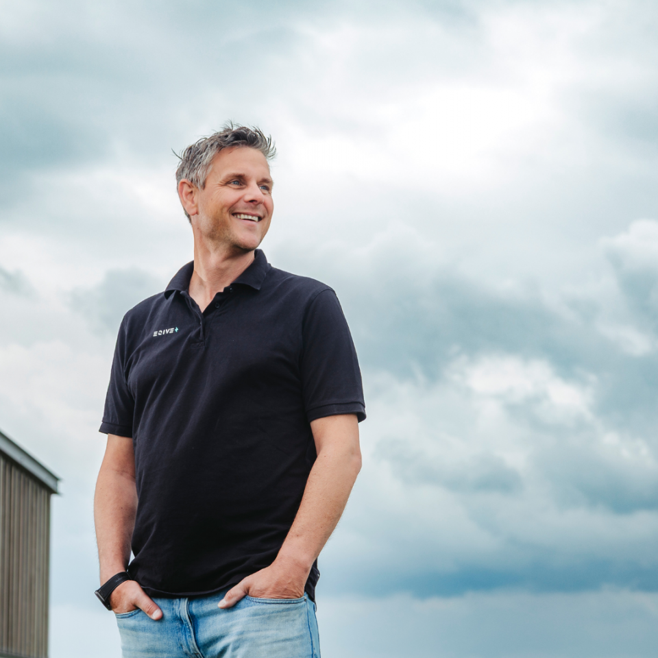 Trotse glimlachende man met bewolkte lucht in de achtergrond
