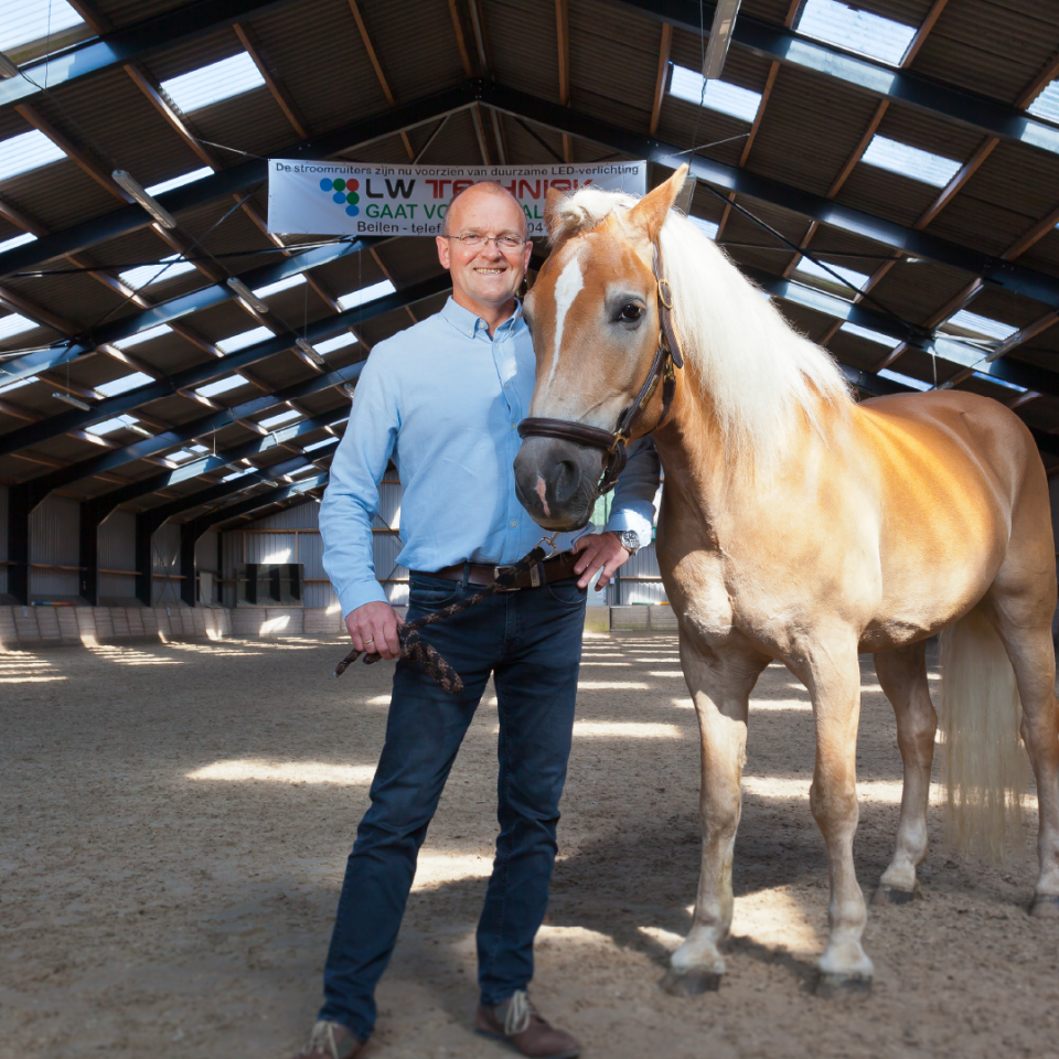 Foto Bert Vos, voorzitter van de Stroomruiters, naast een paard.