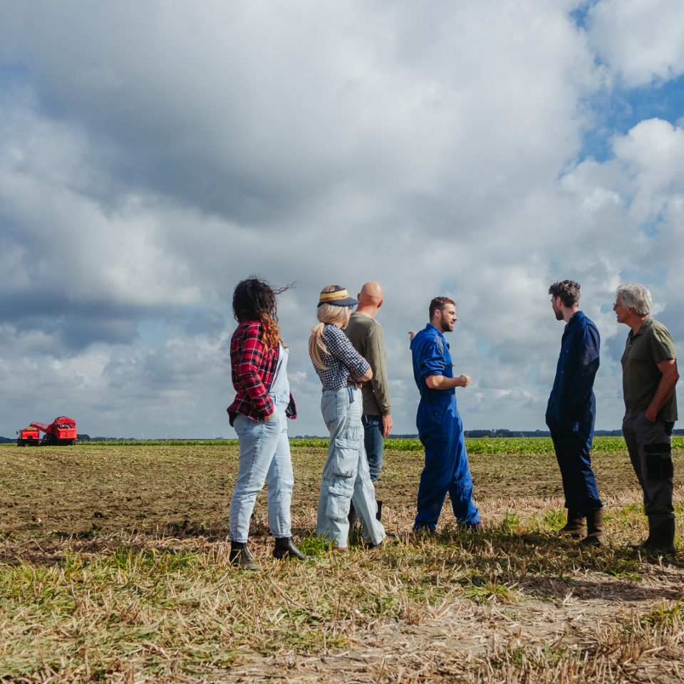 Groep mensen op een geoogst suikerbietenveld praten over plannen voor het gebied