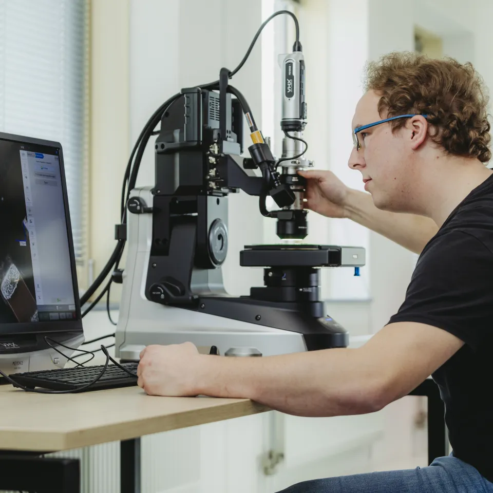 Medewerker werkt met microscoop aan sensor